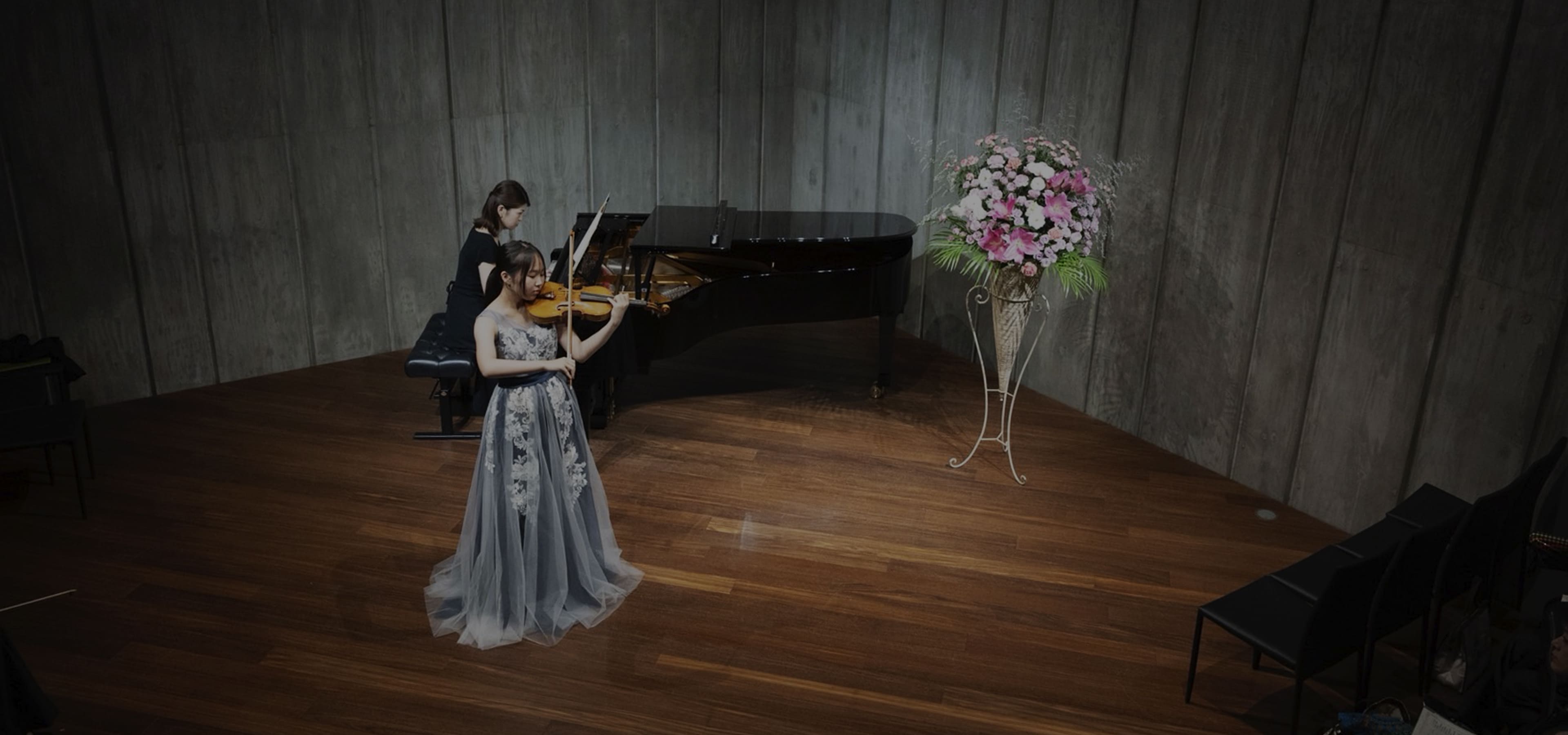 ステージでヴァイオリンを演奏する女性とピアノを弾く女性