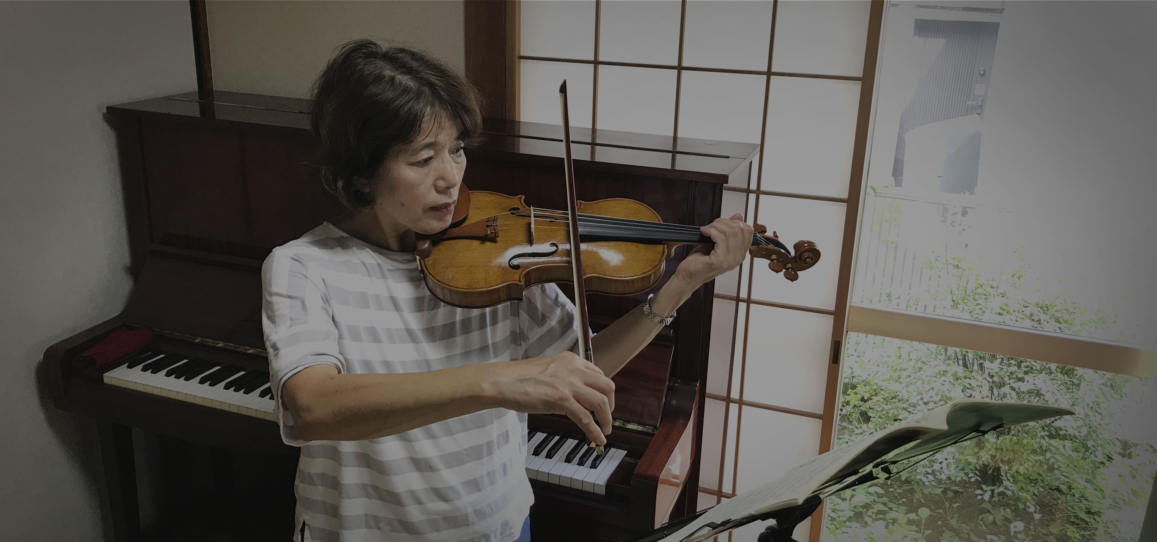 ピアノの前でヴァイオリンを弾く女性